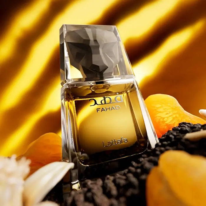 Perfume Fahad de Lattafa Eau de Parfum 80ml, frasco dorado sobre fondo ambarino con flores blancas