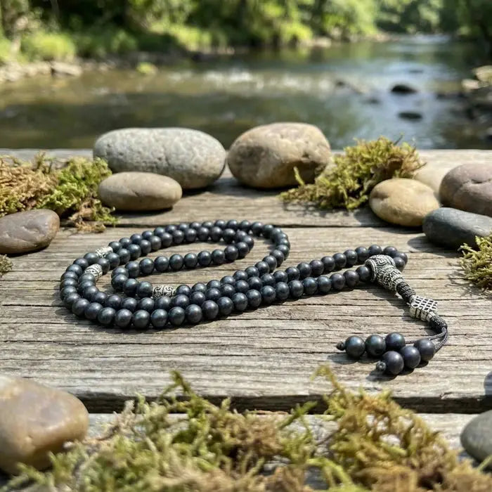 Black  shaligrambeaded necklace on a wooden surface with a natural background