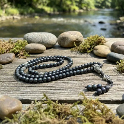 Black  shaligrambeaded necklace on a wooden surface with a natural background