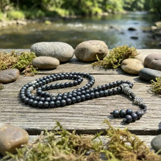 Black  shaligrambeaded necklace on a wooden surface with a natural background