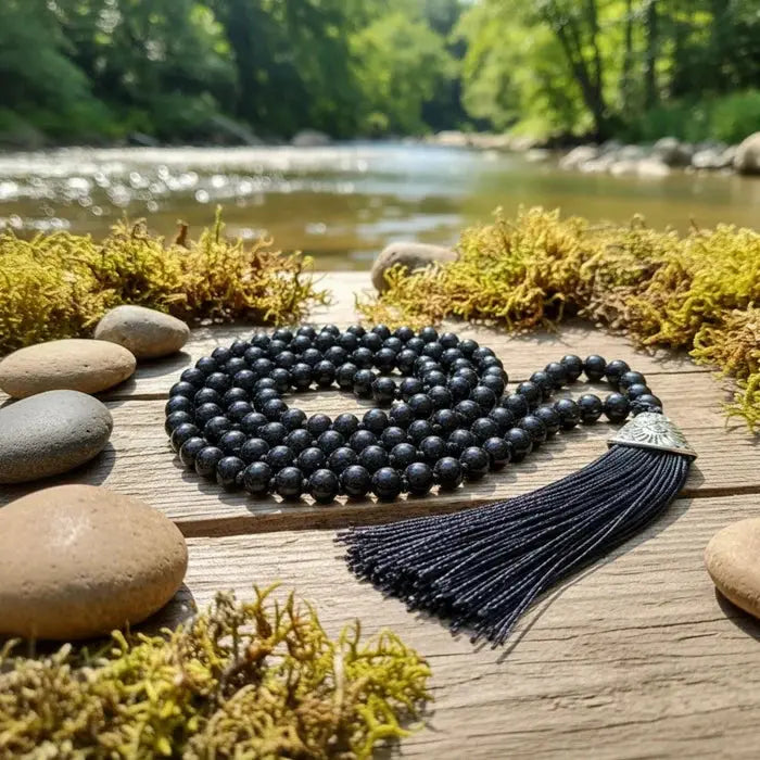 Black beaded necklace with tassel on a wooden platform by a river