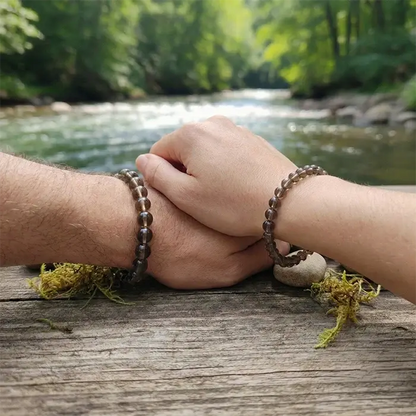 Pareja con pulseras de cuarzo ahumado en las muñecas, foto lifestyle junto a un río | AuryStone